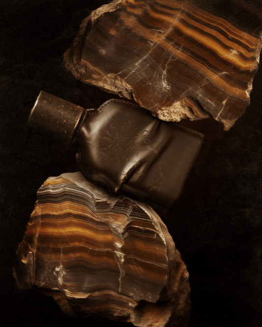 CUOIUM perfume bottle with natural stone background, symbolizing beauty.