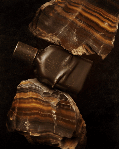 CUOIUM perfume bottle with natural stone background, symbolizing beauty.