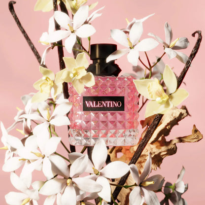 Donna Born In Roma Eau de Parfum with Bourbon Vanilla & Jasmine bottle among white flowers.